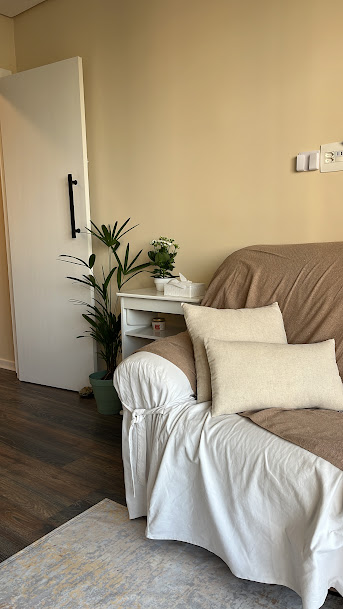 Sala de atendimento psicológico com sofá marrom, plantas e almofada aconchegante